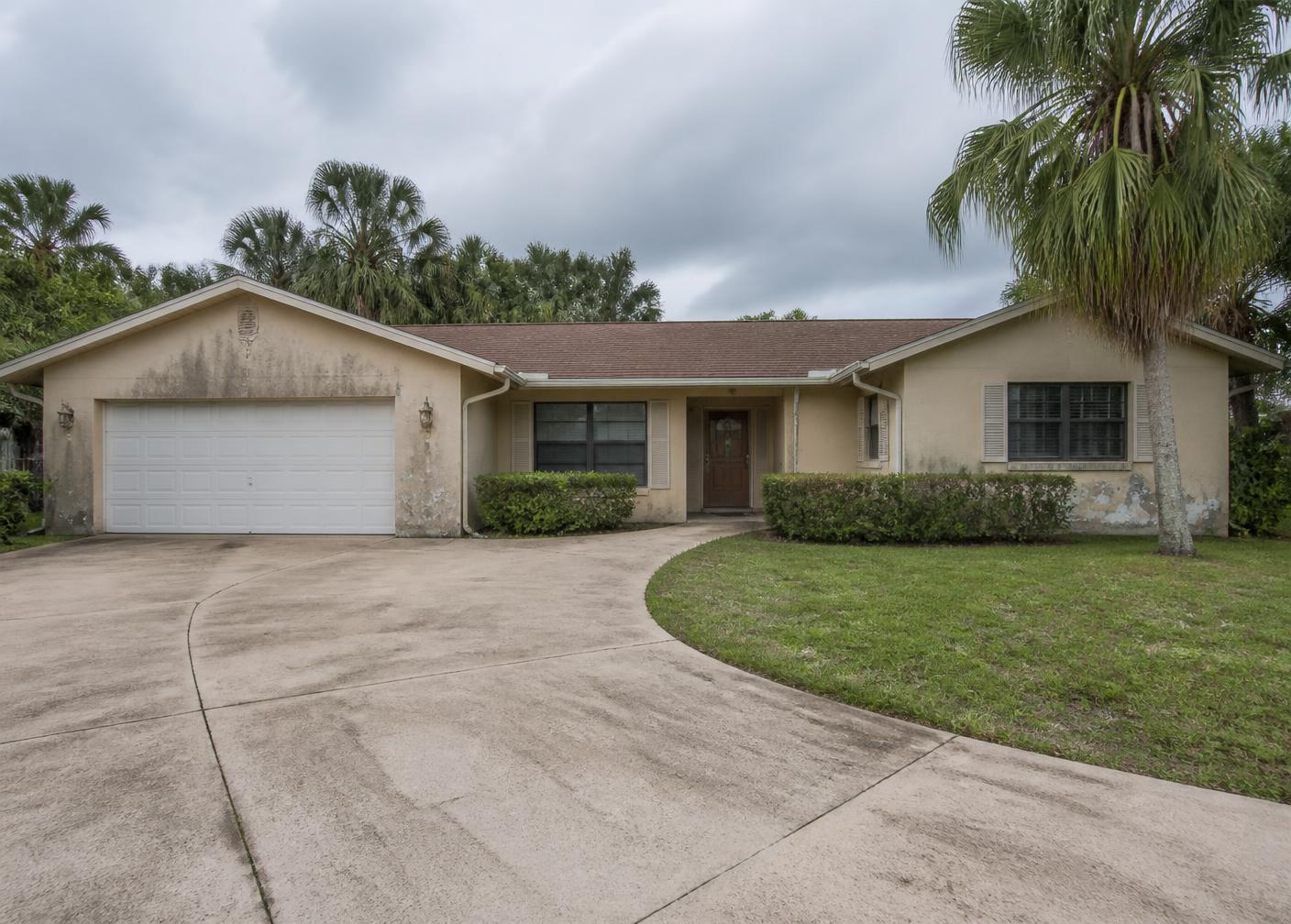Florida home exterior with faded, stained stucco paint before repainting